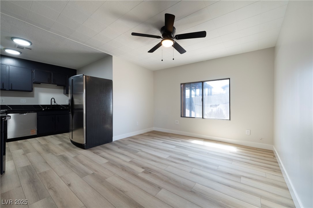 238 Kansas Avenue Henderson, NV 89015 - Photo 8 of 61 Kitchen featuring black fridge, dark countertops, light wood-style floors, dark cabinetry, and ceiling fan