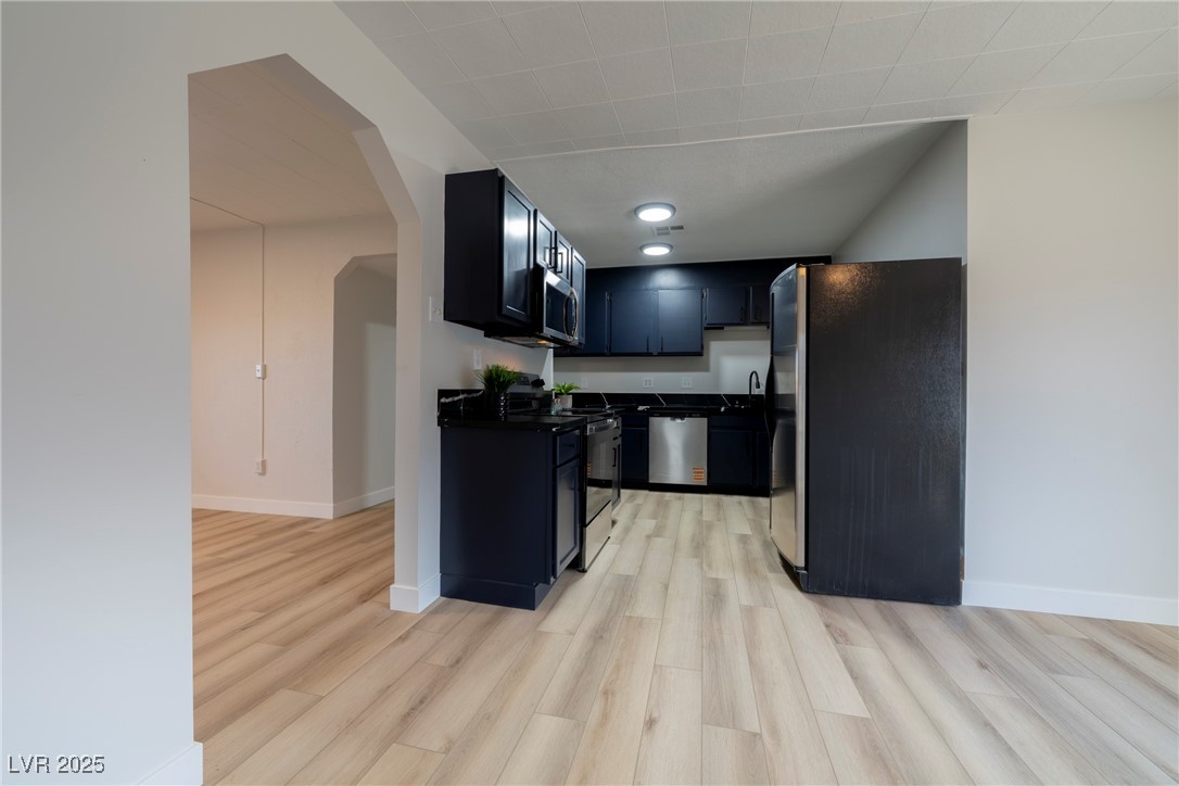 238 Kansas Avenue Henderson, NV 89015 - Photo 9 of 61 Kitchen with arched walkways, appliances with stainless steel finishes, light wood-style flooring, and dark cabinets