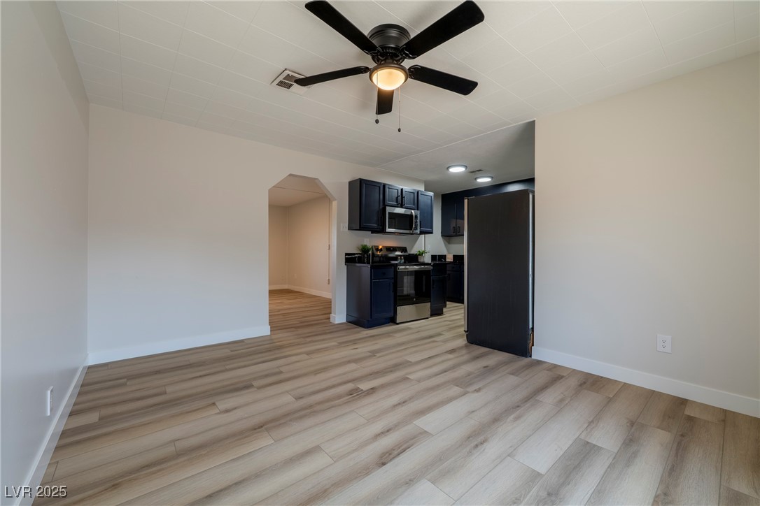 238 Kansas Avenue Henderson, NV 89015 - Photo 10 of 61 Unfurnished living room with arched walkways, light wood-style floors, and ceiling fan