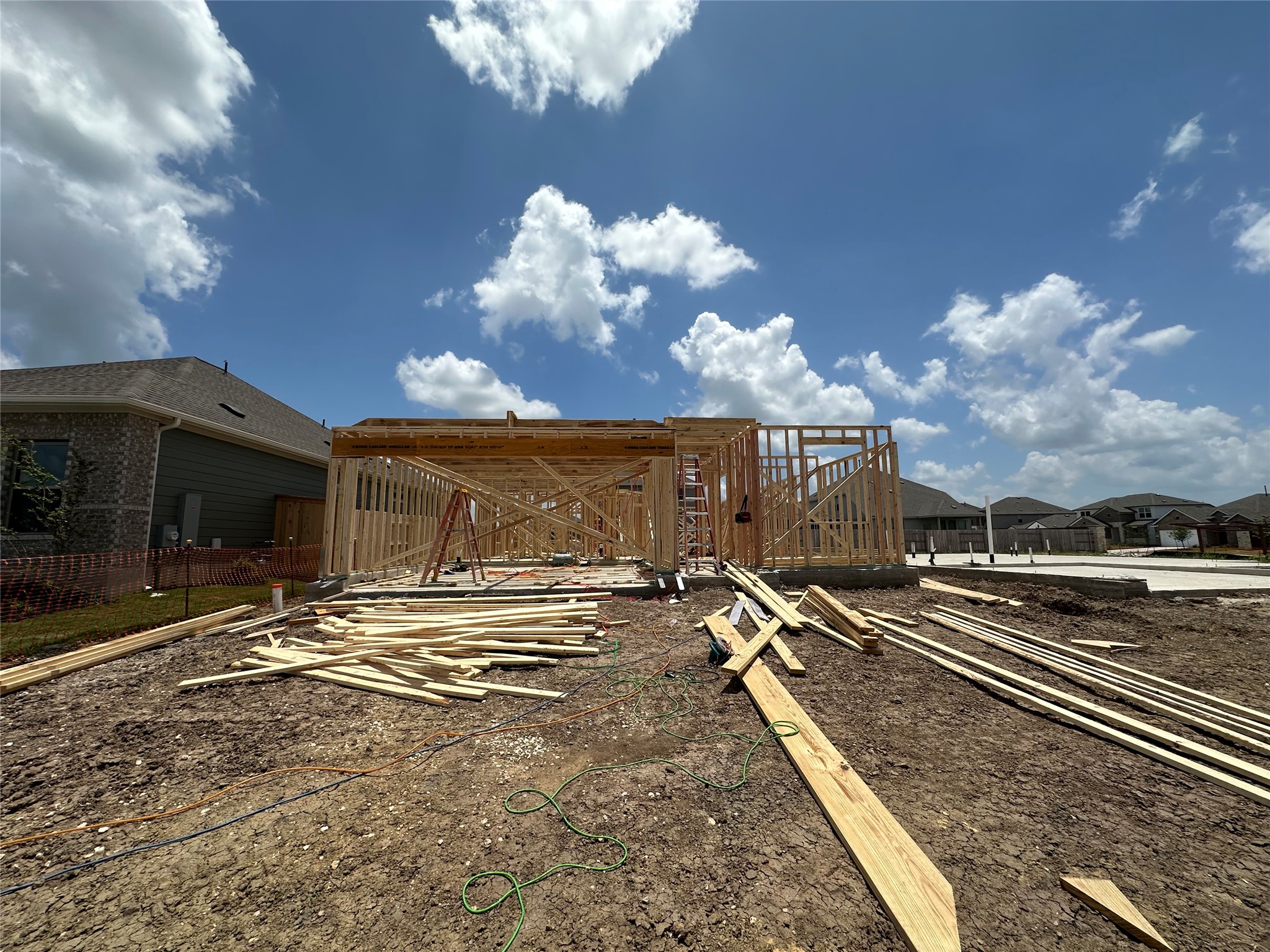 13713 Ryan Range Lane Elgin, TX 78621 - Photo 7 of 25 Witness the beginnings of a future residence with solid wood framing under a vast blue sky.