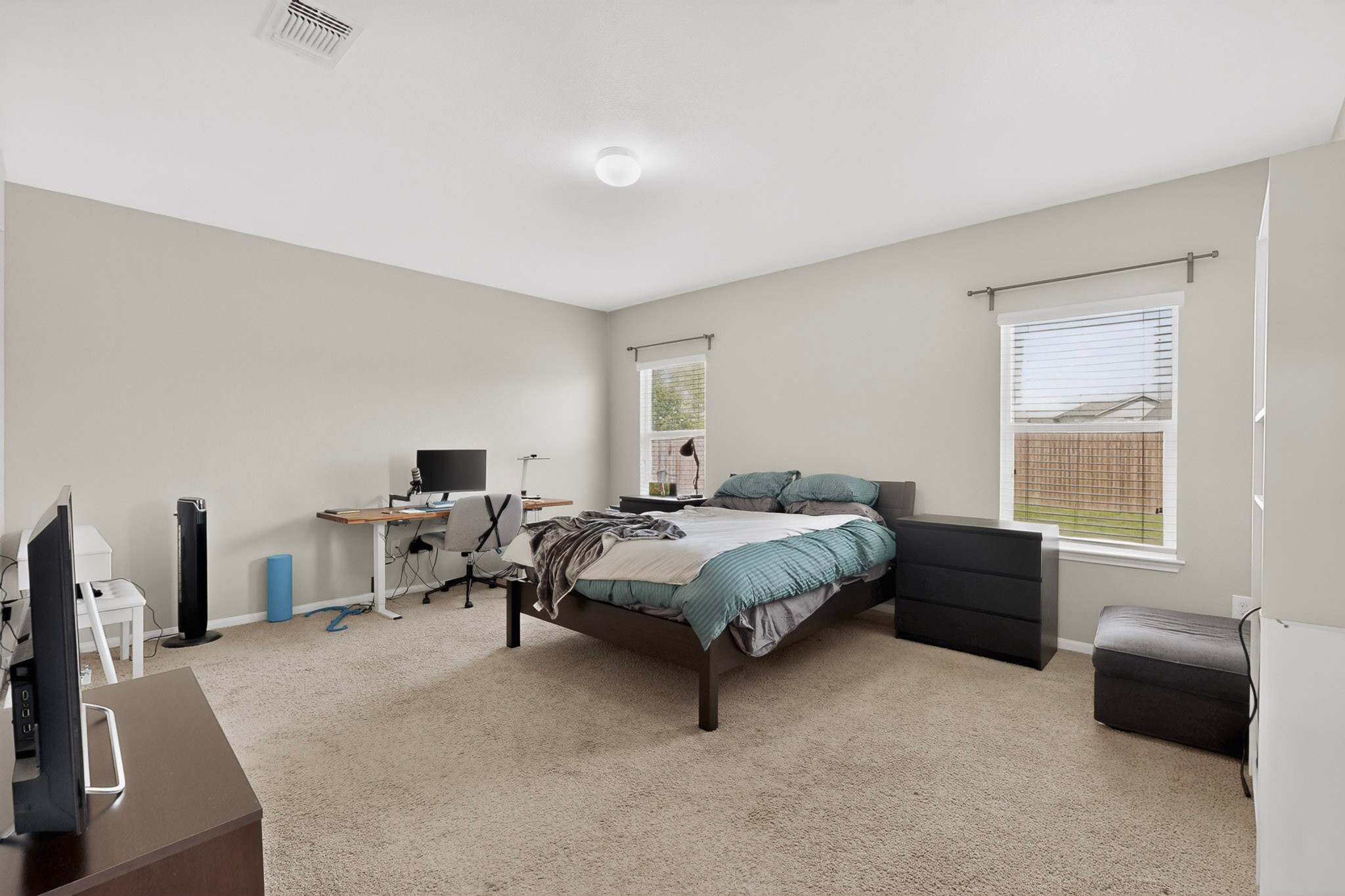 14513 Esker Road Manor, TX 78653 - Photo 16 of 38 master Bedroom, well-lit sleeping quarters with plush carpeting and ample space for a home office setup.