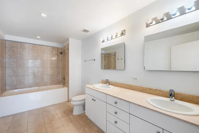 a bathroom with a double vanity sink toilet mirror and bathtub