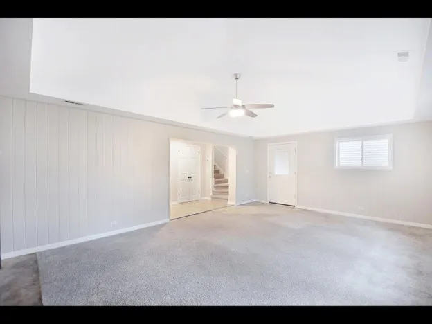 a view of an empty room with chandelier fan and window