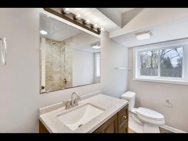 a bathroom with a sink toilet a mirror and window