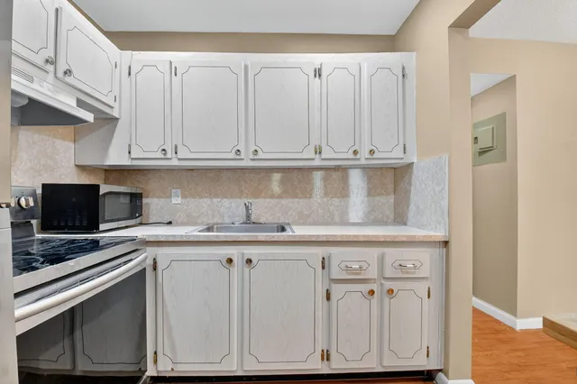 a kitchen with granite countertop white cabinets and a stove