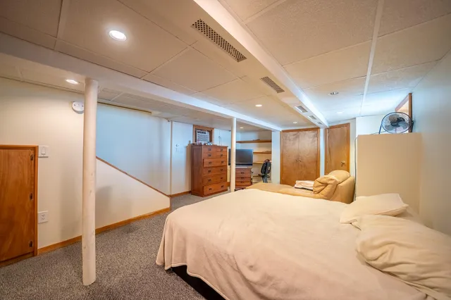 a large bedroom with a bed and wooden floor