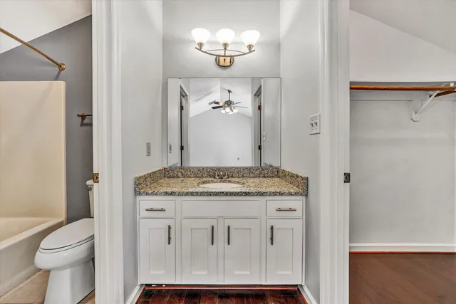 a bathroom with a granite countertop sink a toilet and shower