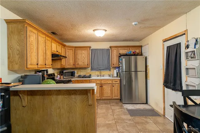 a kitchen with a refrigerator a stove a sink a counter top space and cabinets