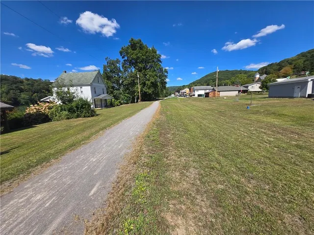 a view of open pool with lawn chairs and a large tree