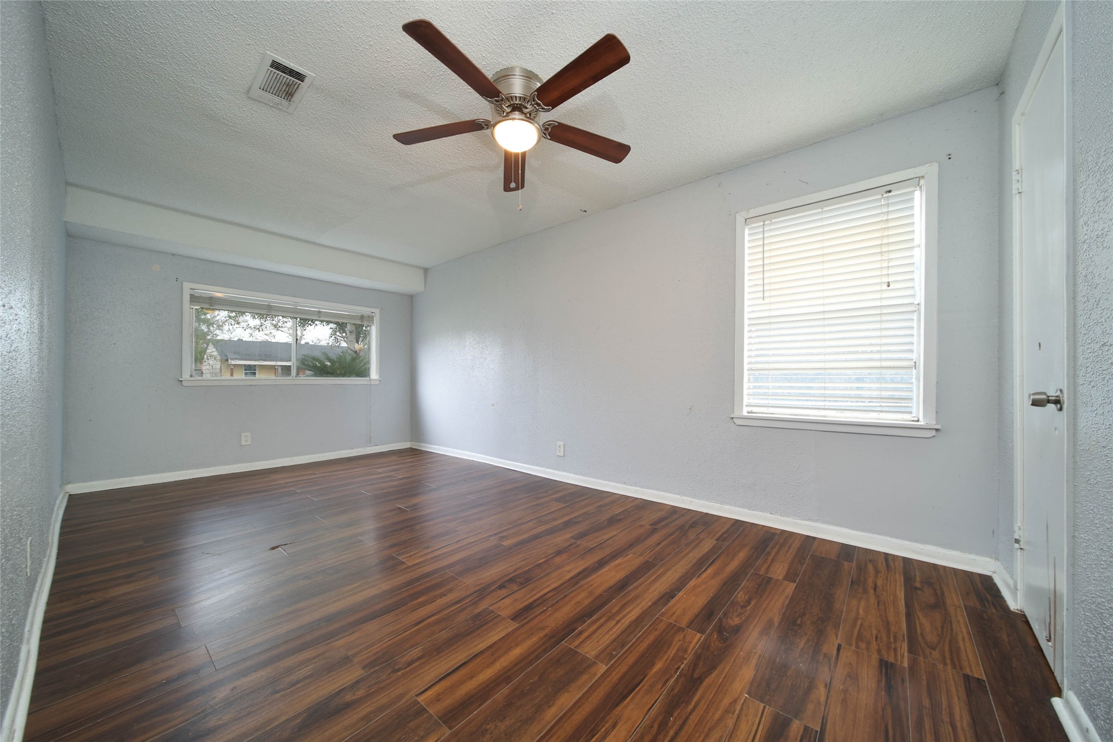 8718 Pattibob Street Houston, TX 77029 - Photo 11 of 14 an empty room with wooden floor windows and fan