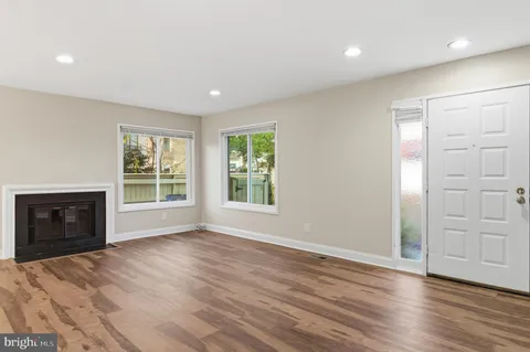 an empty room with wooden floor cabinet and windows