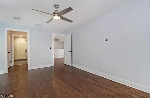an empty room with wooden floor and a ceiling fan