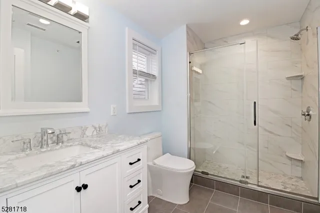 a bathroom with a granite countertop sink toilet a mirror and shower
