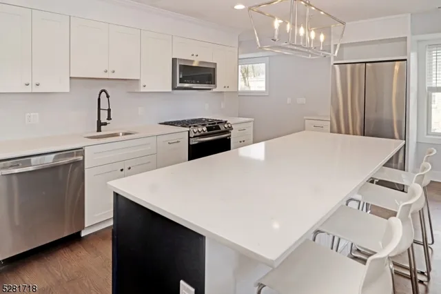 a kitchen with stainless steel appliances a sink a stove a refrigerator and cabinets