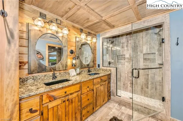 a bathroom with a granite countertop sink a mirror and shower