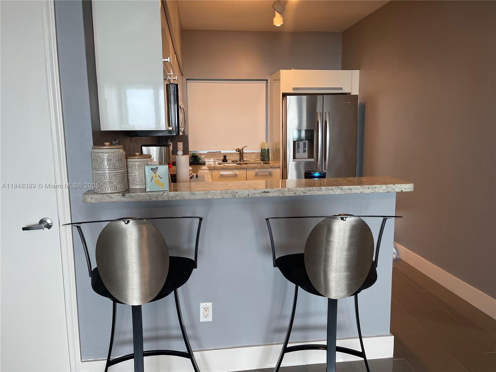 601 Northeast 36th Street, Unit 1009 Miami, FL 33137 - Photo 7 of 19 a kitchen with kitchen island a counter space a sink and a refrigerator