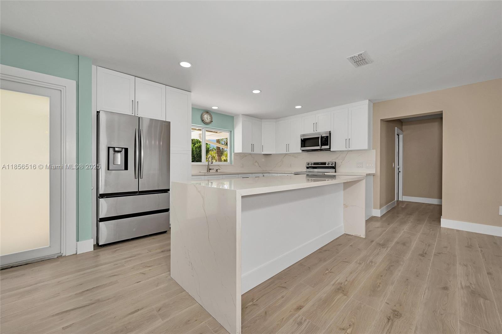 5885 Pine Tree Drive Sanibel, FL 33957 - Photo 21 of 56 a kitchen with white cabinets and stainless steel appliances
