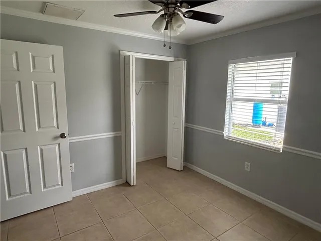 an empty room with windows and fan