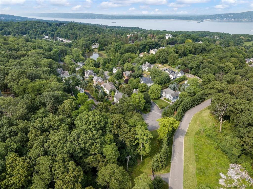 an aerial view of a residential houses with outdoor space and trees all around