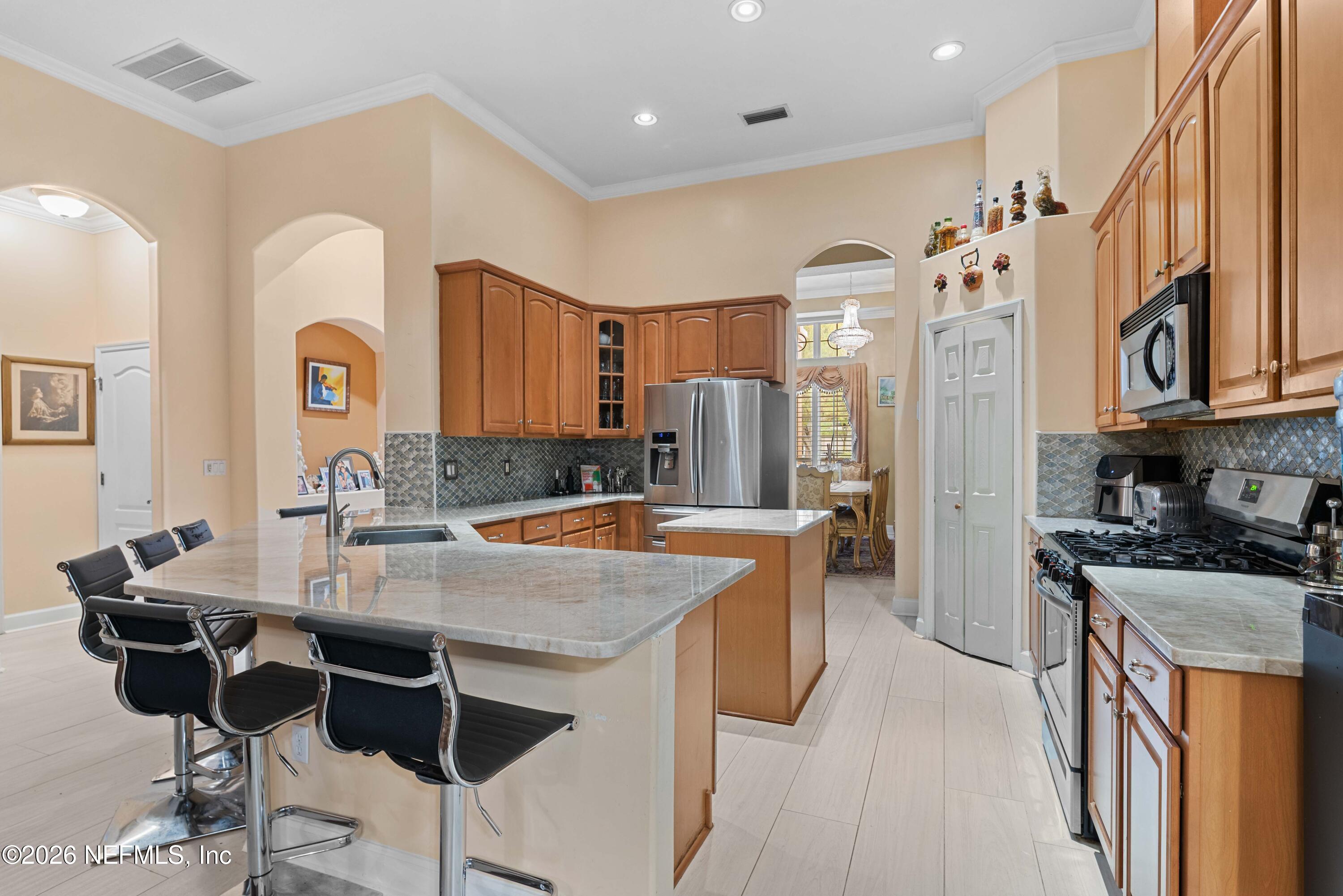 5983 Wakulla Springs Road Jacksonville, FL 32258 - Photo 8 of 31 a kitchen with stainless steel appliances granite countertop a stove top oven a sink a refrigerator and chairs