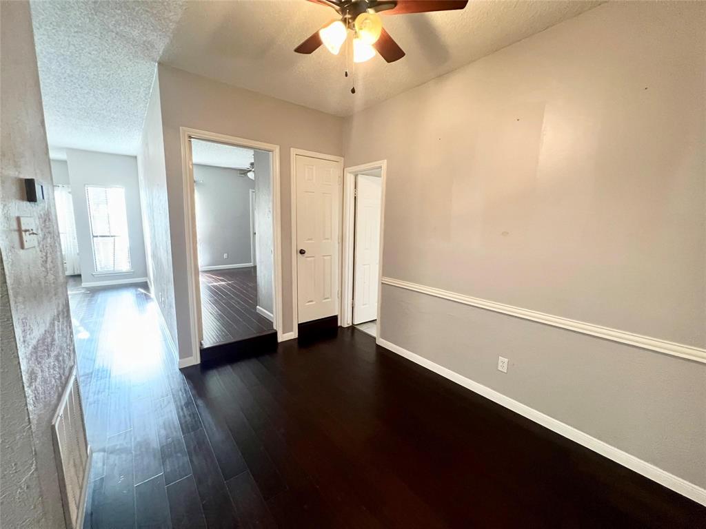 2105 Count Fleet Drive, Unit 207 Arlington, TX 76011 - Photo 11 of 17 an empty room with wooden floor chandelier fan and windows