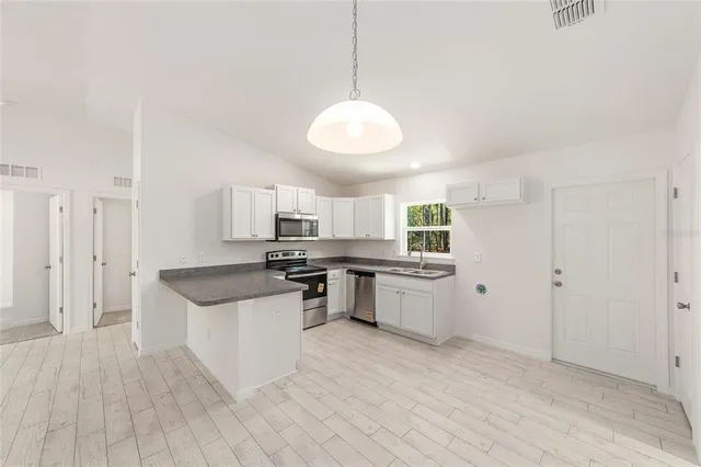 a kitchen with kitchen island granite countertop a sink a stove a counter top space and cabinets