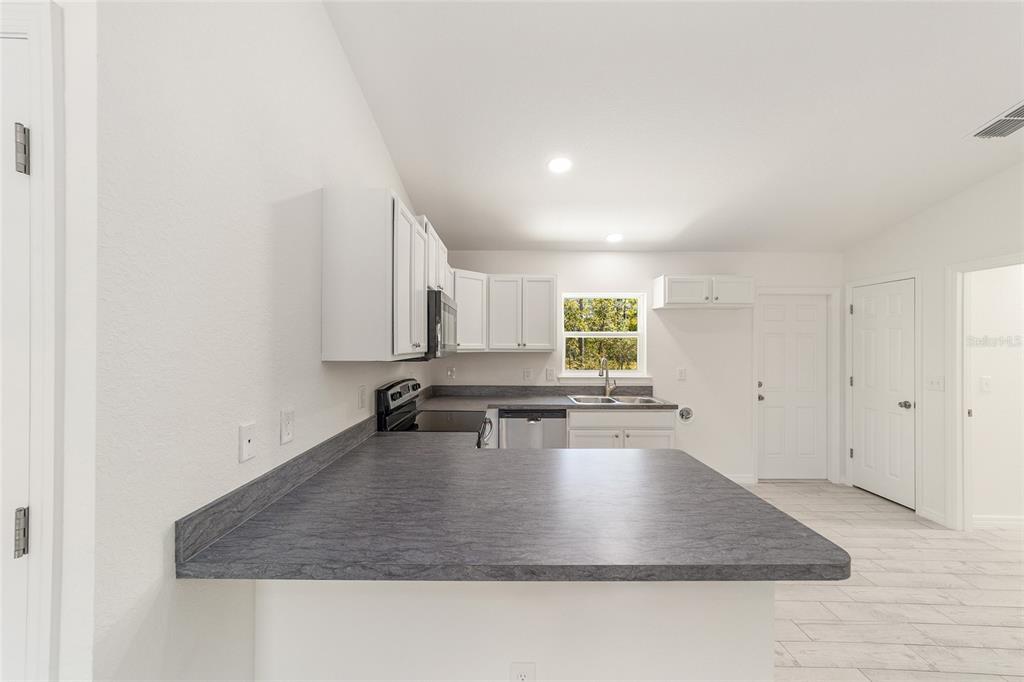 284 Southwest Commodore Road Dunnellon, FL 34431 - Photo 17 of 48 a kitchen with kitchen island granite countertop a sink a stove a counter top space and cabinets