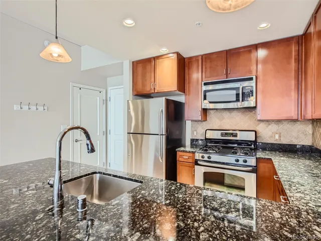 a kitchen with stainless steel appliances granite countertop a stove a sink and a microwave