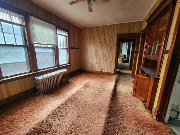 a view of an empty room with wooden floor and stairs