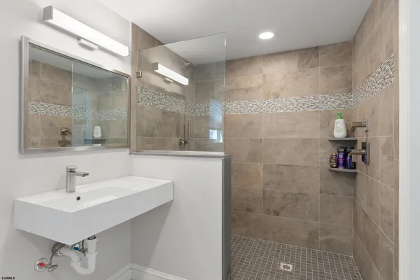 a bathroom with a sink shower and a mirror