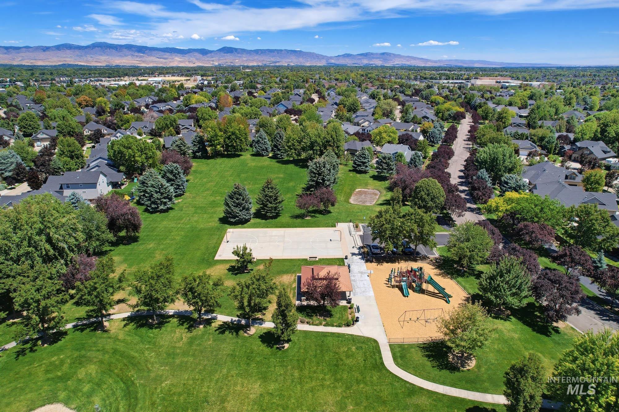 2172 West Cedar Grove Street Meridian, ID 83646 - Photo 49 of 49 Expansive community park featuring a manicured lawn, established trees, a playground area, a sports court, and a paved walking path, surrounded by a residential neighborhood