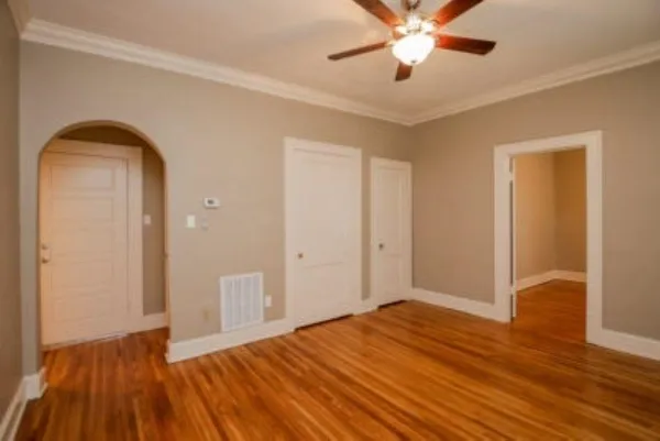 a view of empty room with wooden floor and fan