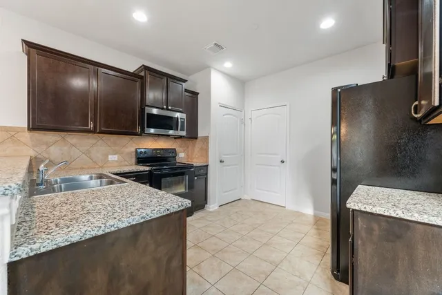 a kitchen with stainless steel appliances granite countertop a refrigerator and a stove top oven