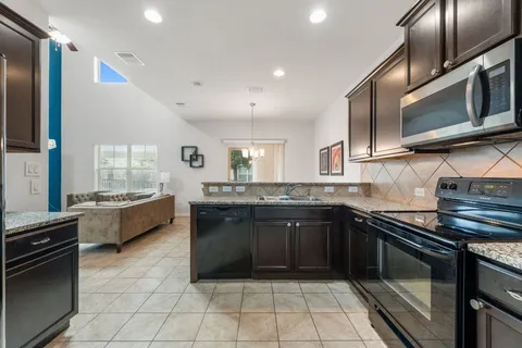 a large kitchen with stainless steel appliances granite countertop a stove a sink and a microwave