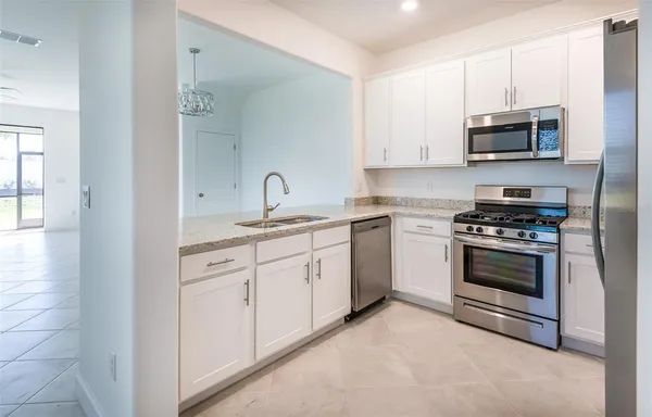 a kitchen with stainless steel appliances granite countertop grey cabinets a stove a sink and dishwasher