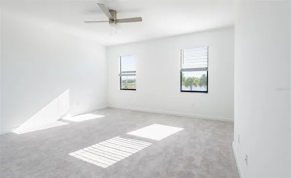 an empty room with windows and fan