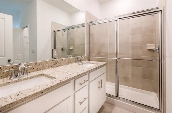 a bathroom with a granite countertop sink a mirror and a shower