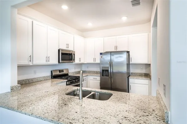 a kitchen with granite countertop a refrigerator and a sink