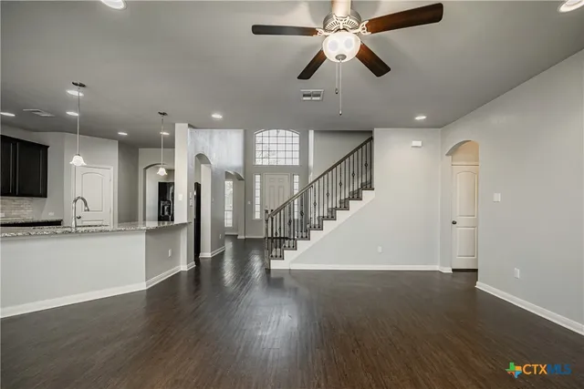 a view of a hallway with wooden floor a ceiling fan and a kitchen