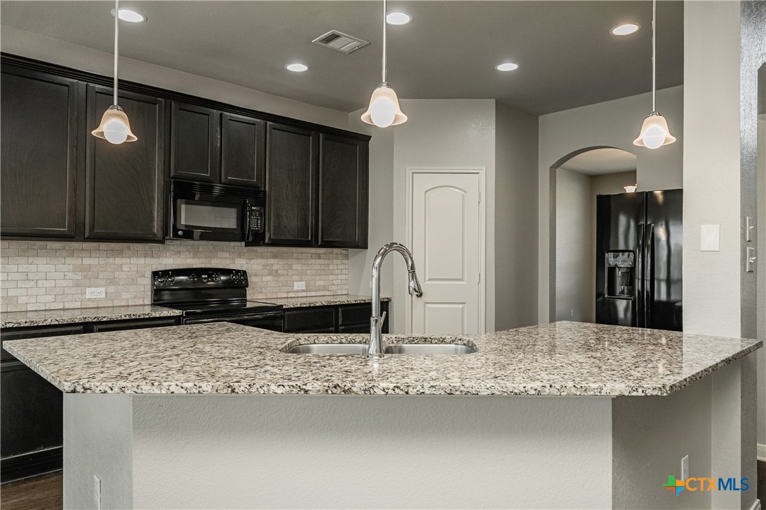 7848 Old Gate Road Temple, TX 76502 - Photo 13 of 32 a kitchen with granite countertop a sink a counter top space appliances and cabinets