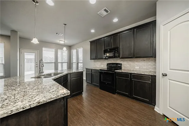a kitchen with stainless steel appliances granite countertop wooden cabinets a stove top oven a sink and dishwasher