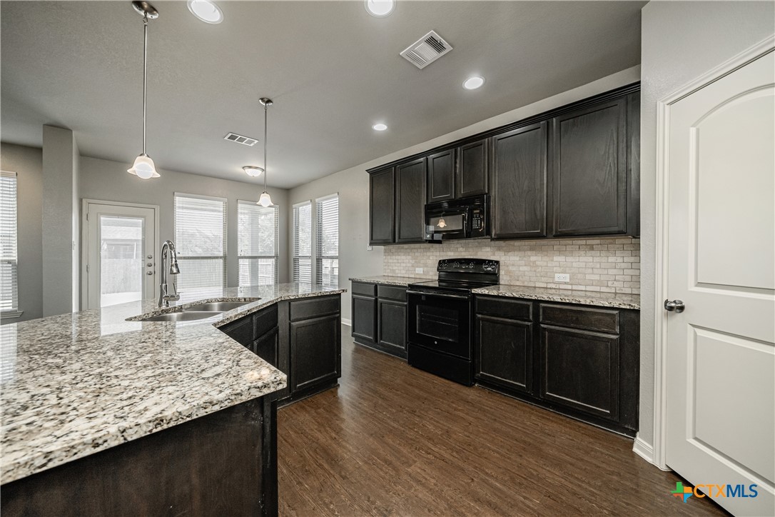 7848 Old Gate Road Temple, TX 76502 - Photo 14 of 32 a kitchen with stainless steel appliances granite countertop wooden cabinets a stove top oven a sink and dishwasher