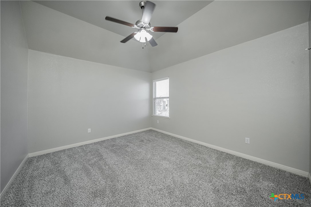 7848 Old Gate Road Temple, TX 76502 - Photo 28 of 32 an empty room with a chandelier fan and windows