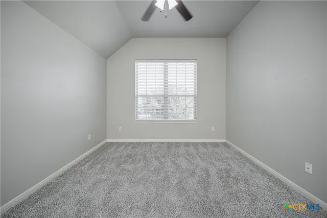 an empty room with chandelier fan and windows