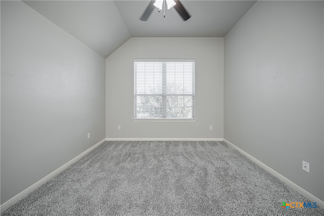7848 Old Gate Road Temple, TX 76502 - Photo 29 of 32 an empty room with chandelier fan and windows