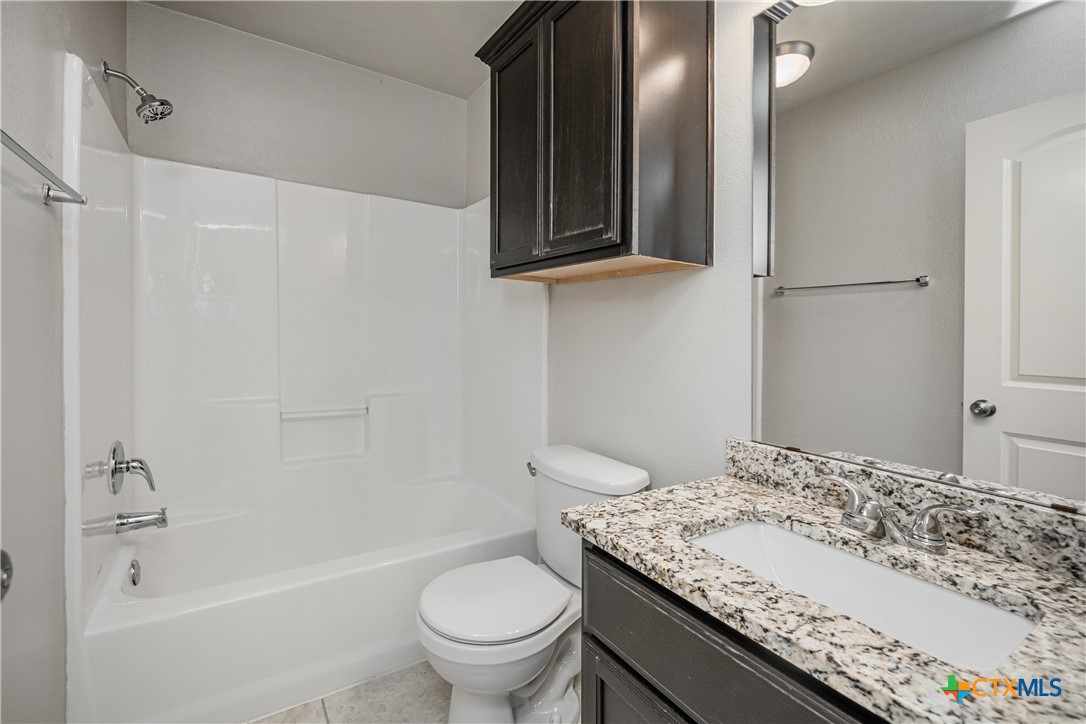 7848 Old Gate Road Temple, TX 76502 - Photo 30 of 32 a bathroom with a granite countertop sink toilet and shower