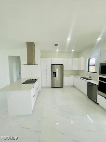 a large kitchen with stainless steel appliances granite countertop a large stove top oven a sink dishwasher and a refrigerator with wooden floor