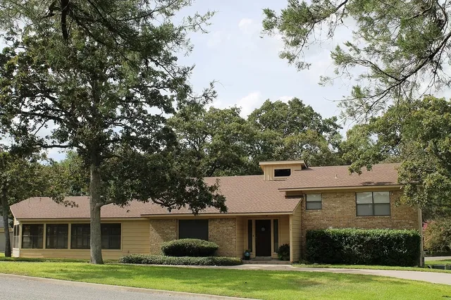 a front view of a house with a garden and trees