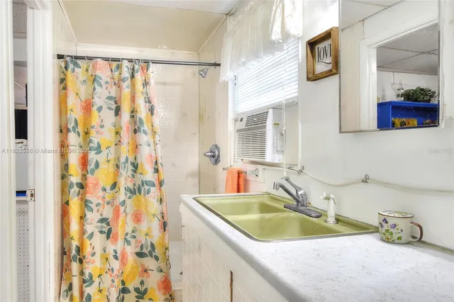 a bathroom with a granite countertop sink a mirror and shower