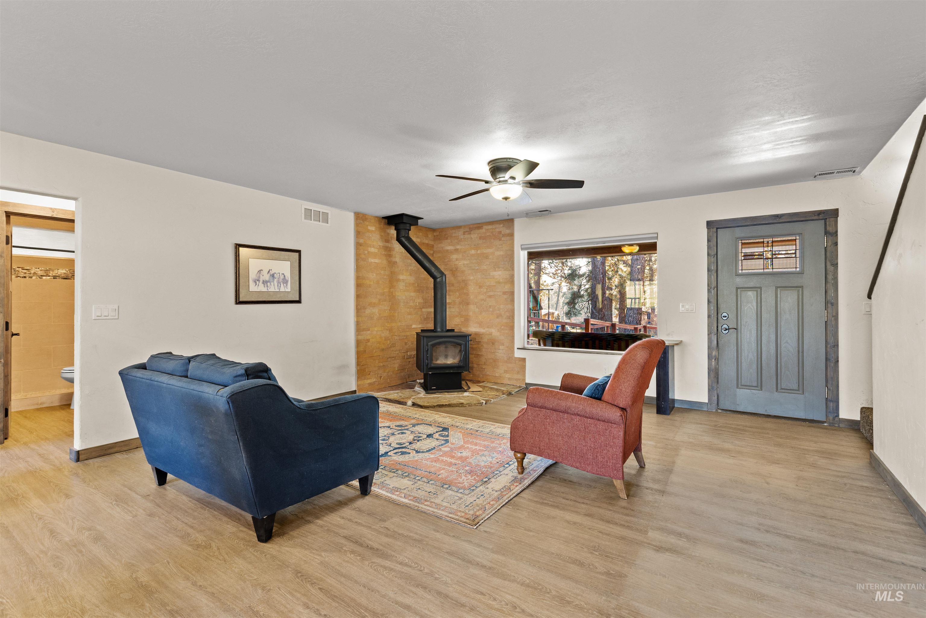 3488 Ward Road Cambridge, ID 83610 - Photo 7 of 50 Living area featuring a wood stove, light wood-style flooring, and ceiling fan